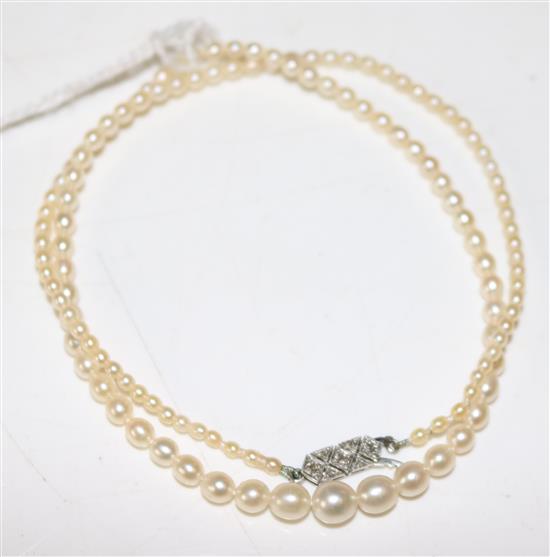 Single strand graduated cultured pearl necklace, with white gold diamond set clasp(-)